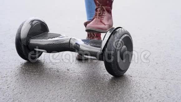 女人没能在沥青路上骑着陀螺滑板车户外自动平衡气垫板上的女性腿特写视频的预览图