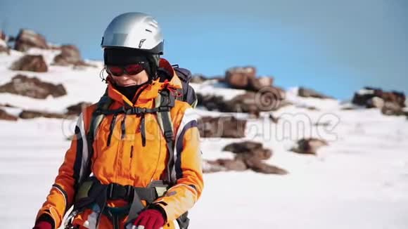 一个穿着装备的登山者站在白雪皑皑的小山上交叉交叉双臂交叉在胸前视频的预览图