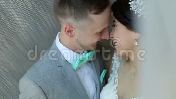 幸福的新婚夫妇站在靠近窗户的怀抱里轻轻地亲吻视频的预览图