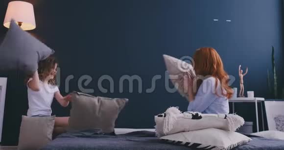 快乐的妈妈姐姐和小女孩在床上享受有趣的枕头大战保姆妈妈带着小女儿视频的预览图