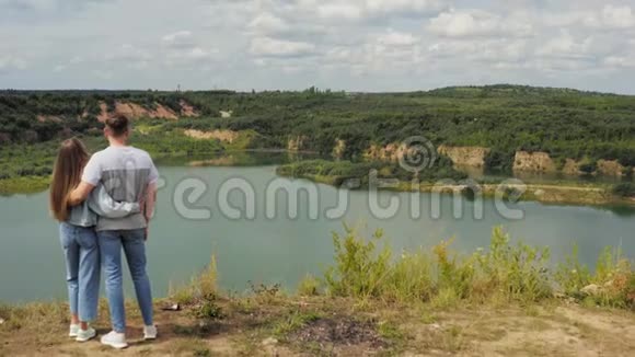 一对夫妇站在湖边的山崖上恋爱中的情侣在美丽景色的背景下拥抱视频的预览图