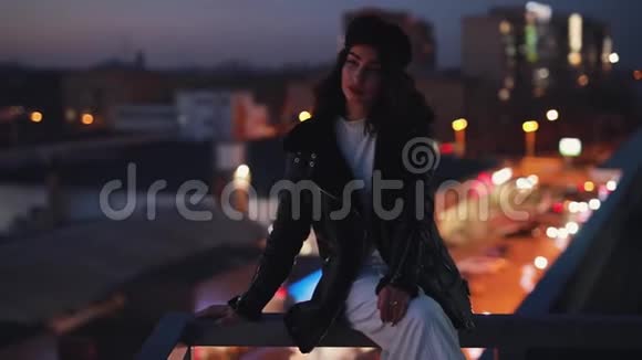 坐在梯田上的女人环顾四周享受夜晚城市的平静视频的预览图