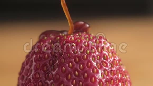 巧克力焦糖糖浆将一股浓稠的水流注入成熟多汁的新鲜红草莓的顶端上面有大颗种子慢慢地往下滴视频的预览图