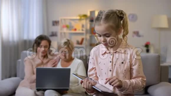 玩平板电脑游戏的孙子母亲和祖父母使用笔记本电脑技术视频的预览图
