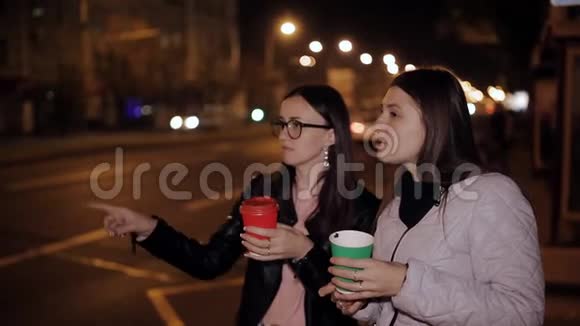 两个在城市散步的女人在公共汽车站喝咖啡玩得开心视频的预览图