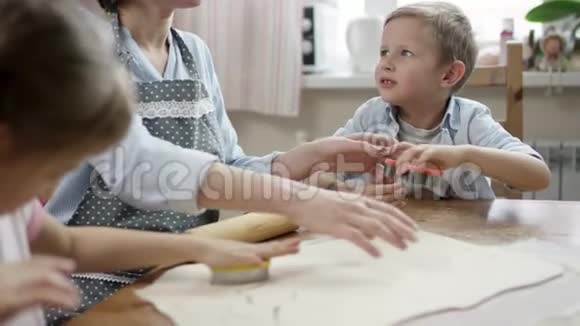妈妈展示如何用正确的方法制作饼干并帮助她的儿子视频的预览图