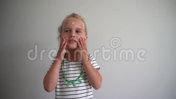 可爱的小女孩在她的脸上涂上奶油万向节运动视频的预览图