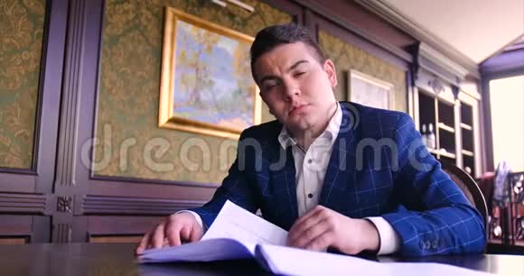 一个年轻的商人坐在别致的办公室里对一份纸合同感到不满拒绝签字生气不愿签字视频的预览图