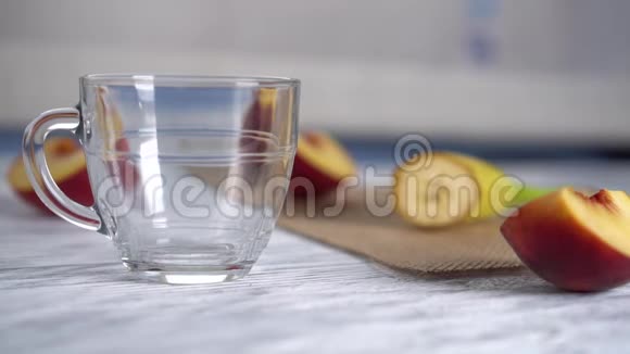桃子汁倒在木桌上的玻璃杯子里上面有桃子切片视频的预览图