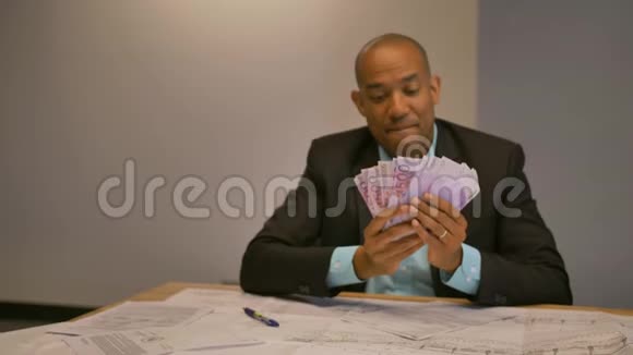 年轻的男企业家在桌上数钱视频的预览图