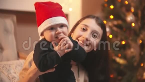 一位微笑的年轻女子抱着她的孩子在圣诞工作室视频的预览图