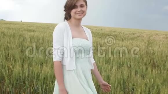 美丽的少女在田野里高高的绿色小麦穗中年轻快乐的女人享受夏天人与人的和谐视频的预览图