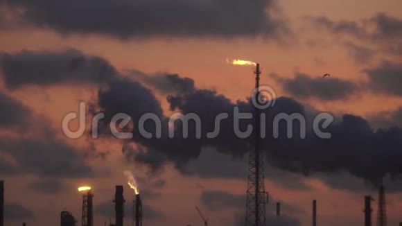 日落时分炼油厂的煤气管道上方燃烧着火焰视频的预览图
