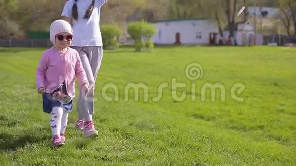 两个姐妹在绿草地上玩耍和奔跑视频的预览图