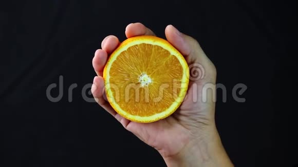 女性的手在黑色背景上挤压橙色视频的预览图