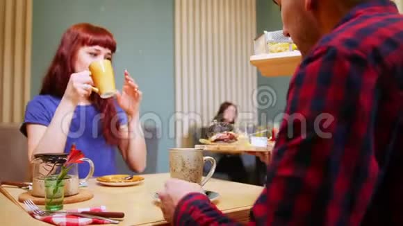 一对夫妇坐在一家咖啡馆的桌子旁喝茶服务员点菜视频的预览图