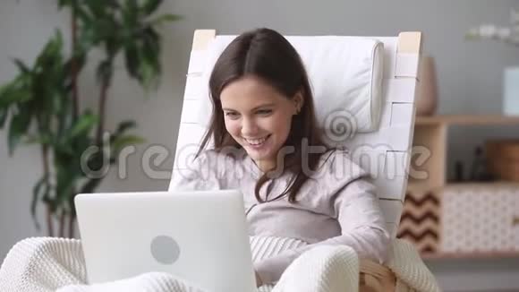 快乐少女喜欢坐在摇椅上使用笔记本电脑视频的预览图