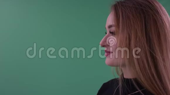美丽快乐体贴的年轻女子穿着黑色便服在绿色的面前侧着身子摆姿势视频的预览图