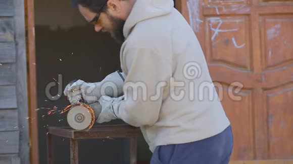 有胡子的工人戴上手套用磨料机锯管子视频的预览图