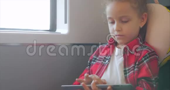 可爱的小女孩用平板娱乐儿童休闲时间乘坐电动火车玩手机游戏视频的预览图