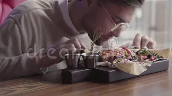 戴眼镜的英俊男子在不使用餐具的情况下吃他的食物顾客在咖啡馆里吃烤鱼视频的预览图