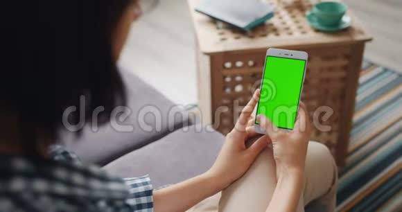 女孩触摸绿色模拟屏幕的现代智能手机使用设备在家里视频的预览图