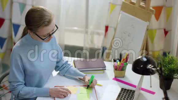 年轻女子在笔记本上用棍子笔记画画视频的预览图