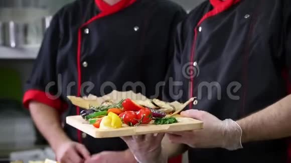 餐厅厨房两个男厨师做完菜后摆出一副毕恭毕敬的手势视频的预览图