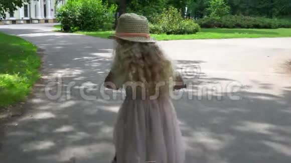 优雅的女孩子带帽子穿粉色连衣裙在户外骑自行车视频的预览图
