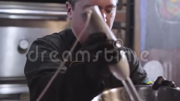 厨师穿着制服和黑色橡胶厨师手套用搅拌机在大铝碗里搅拌准备食物视频的预览图