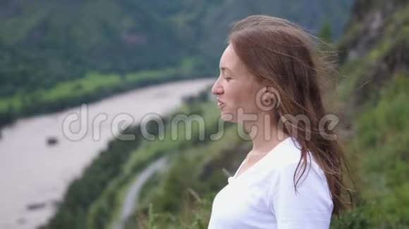 旅游妇女微笑着在山顶上飞舞的头发慢动作视频的预览图