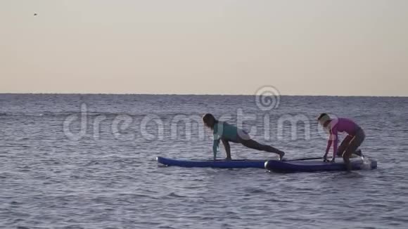 两个女人在水中冲浪板上摆姿势动作缓慢视频的预览图