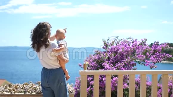 从露台上看到美丽的海景有一棵开花的树妈妈和宝宝欣赏海天相接假期与视频的预览图