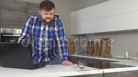 一个男人把咖啡洒在厨房里手提电脑后面清理掉的咖啡慢节奏卫生视频的预览图