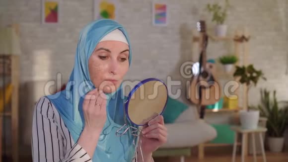 戴着头巾的穆斯林妇女从镜子里看着她脸上烧伤的伤疤视频的预览图