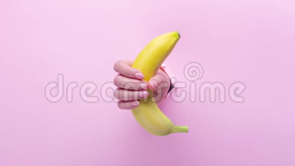 一个女人手里拿着一根香蕉插在一个破粉红纸洞里视频的预览图