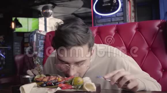 戴眼镜的英俊男子在不使用餐具的情况下吃他的食物满意的顾客吃烤鱼视频的预览图