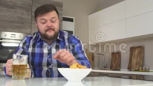 有胡子的胖子在厨房里吃薯片喝啤酒吃垃圾食品慢悠悠抄空间视频的预览图
