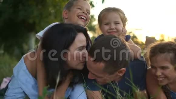 村里的家庭假日夫妻两个带着三个孩子玩得很开心躺在草地上晒太阳视频的预览图