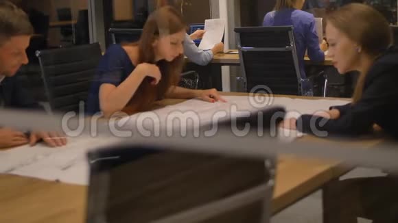 在现代化的办公室里三名工作人员在桌子旁看着报纸和谈话扔出格拉斯的视野视频的预览图