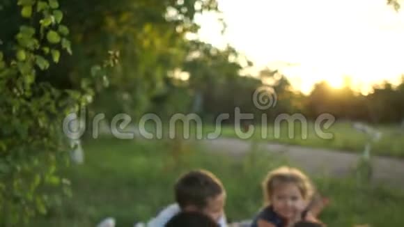幸福的年轻家庭有三个孩子躺在村里的草地上休息暑假家庭日视频的预览图