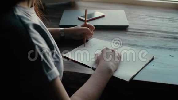 一个年轻女人的手用铅笔在纸上画得紧紧的视频的预览图