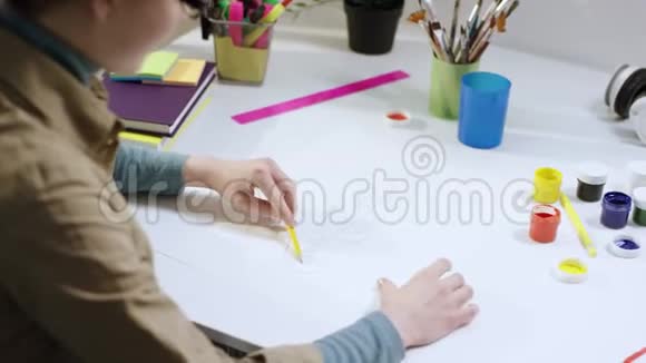 年轻的女艺术家在笔记本上画画看着相机视频的预览图