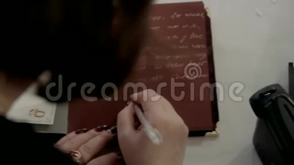 红色的书女人在笔记本上写字视频的预览图