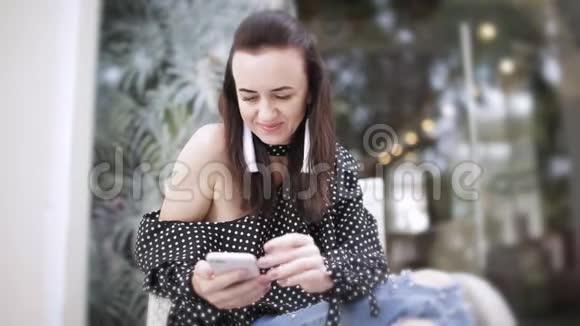 年轻的美女坐在街头咖啡馆在户外咖啡馆用智能手机上网视频的预览图
