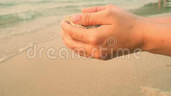 缓慢运动的沙子从手落回海滩视频的预览图