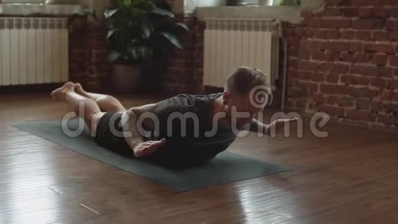 年轻人在室内练习瑜伽瑜伽大师在工作室的黑色垫子上锻炼视频的预览图