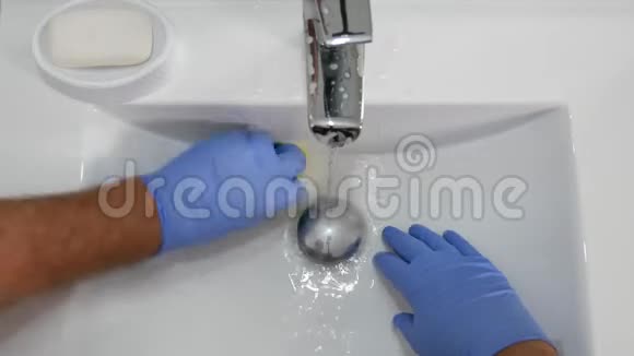 戴手套的人用塑料海绵清洗水槽视频的预览图