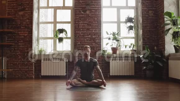 人用砖墙在瑜伽工作室练习莲花姿势做瑜伽姿势的人视频的预览图