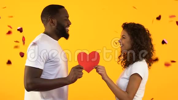非洲裔美国人夫妇在落下的纸屑下捧着纸心结婚纪念日视频的预览图